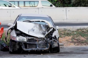 A smashed front end of a silver car accient a front end collision.