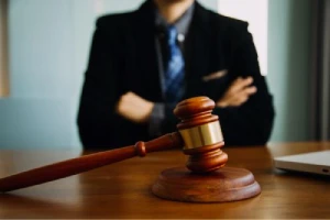 The torso of a personal injury lawyer with hands crossed over his chest in front of a gavel.