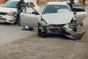 A silver car with front end damage after a passenger side accident.