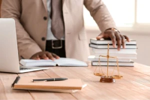 The torso of a personal injury lawyer standing at his desk infront of law books.